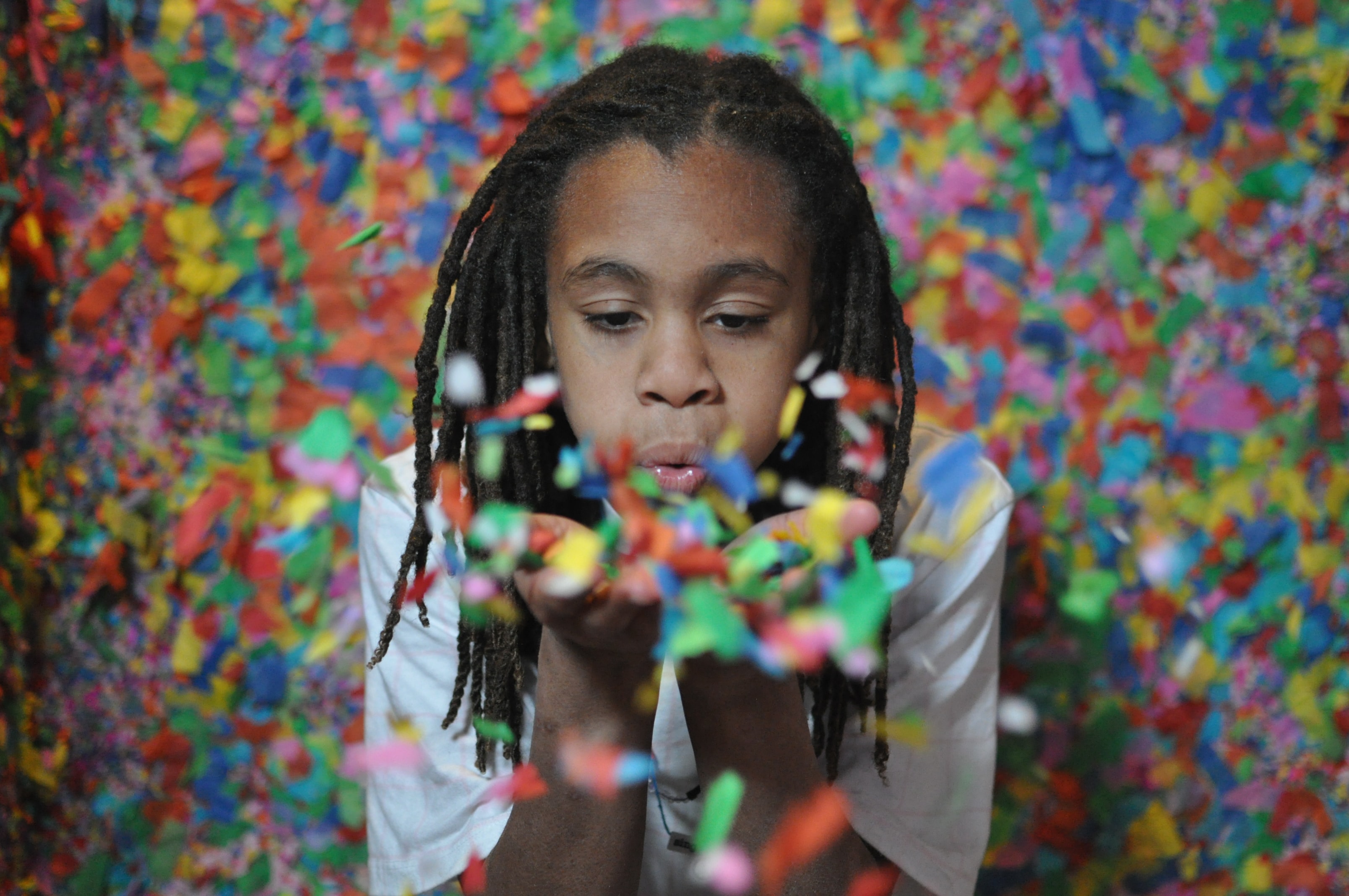 Child blowing colorful confetti with multi-color background